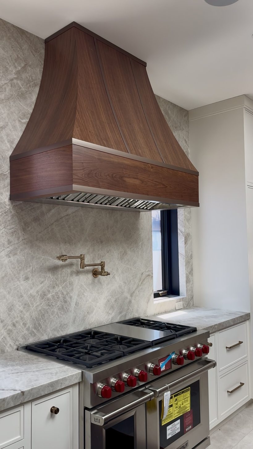 Professional range beneath a custom wood hood in a luxury kitchen
